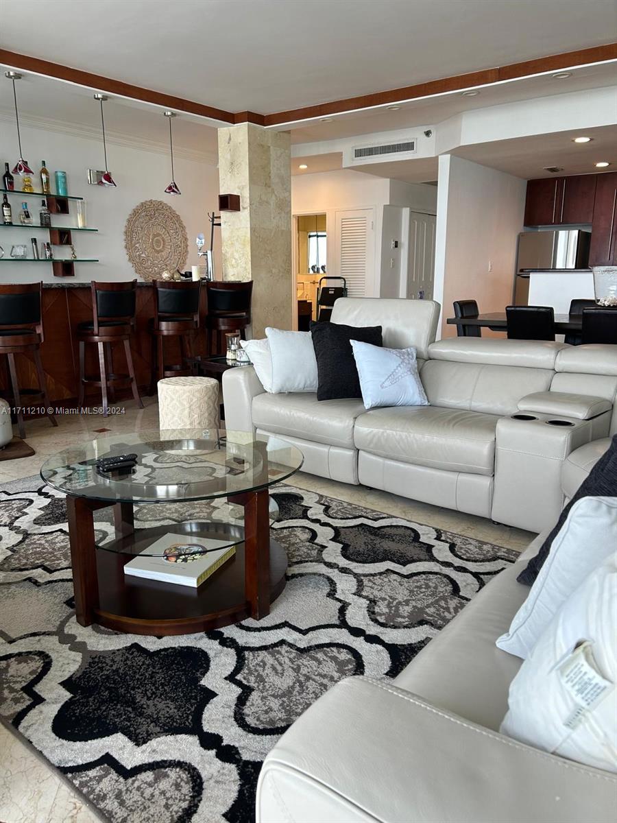 A living room features a glass coffee table, a light-colored sofa, and a home bar — 100 Lincoln Rd, Miami Beach FL 33139, MIAMI BEACH, FL