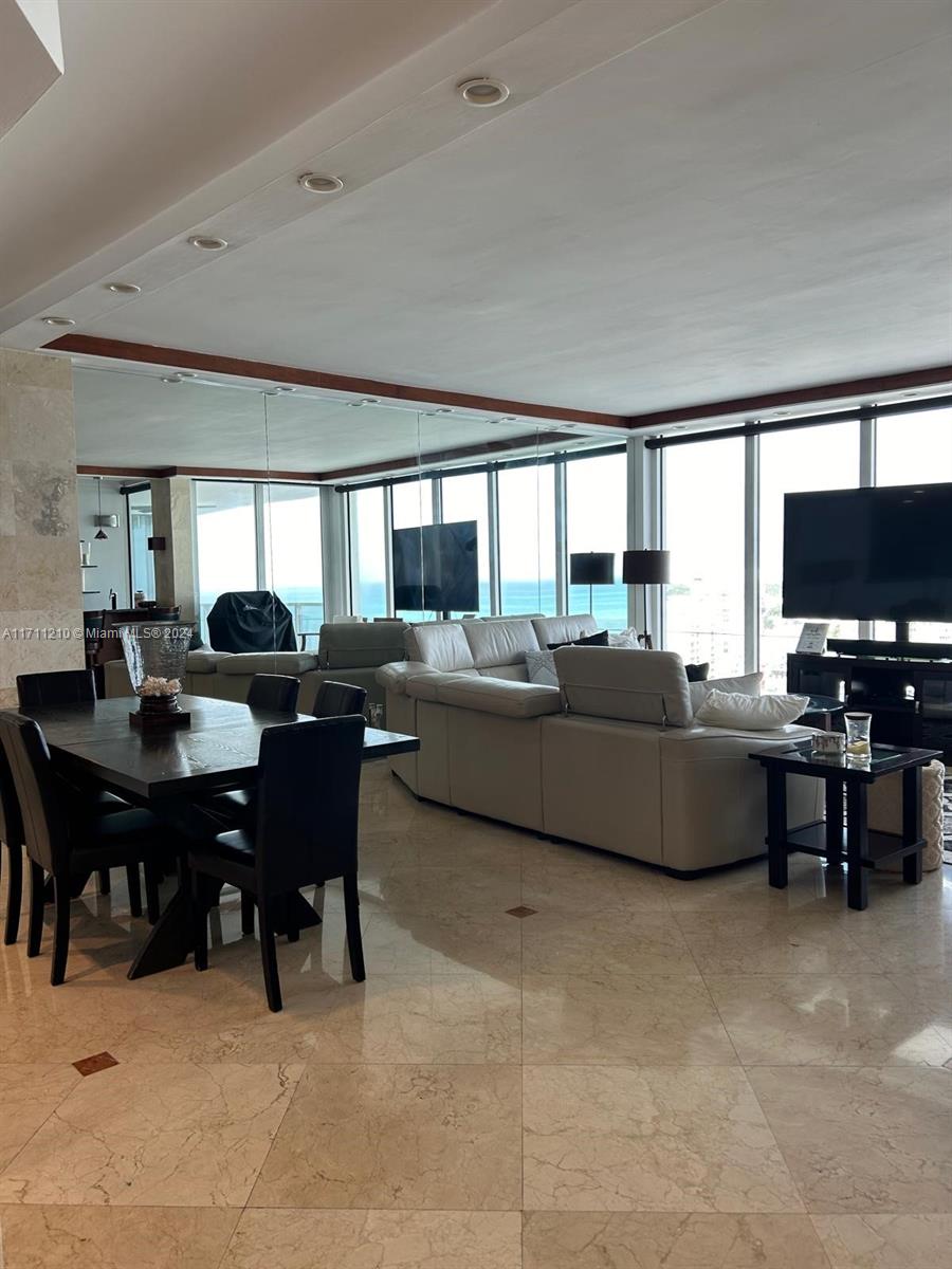 A dining area and living room feature light tile floors, floor-to-ceiling windows, and ocean views — 100 Lincoln Rd, Miami Beach FL 33139, MIAMI BEACH, FL