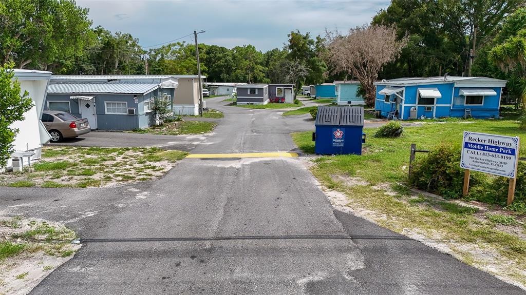 An asphalt road leads through a mobile home park with several small houses and dumpsters — 340 RECKER HIGHWAY, AUBURNDALE, FL