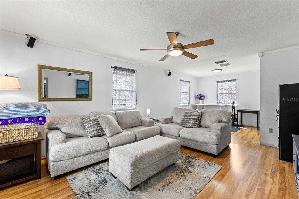 A living room features a wall-mounted television, a ceiling fan, and light-colored sectional seating — 11119 MAHIN LANE, RIVERVIEW, FL