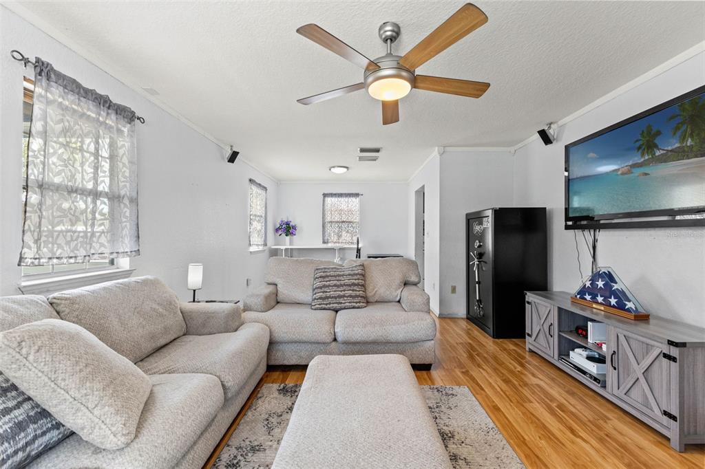 A living room features light-colored sofas, a matching ottoman, wood flooring, and a ceiling fan — 11119 MAHIN LANE, RIVERVIEW, FL