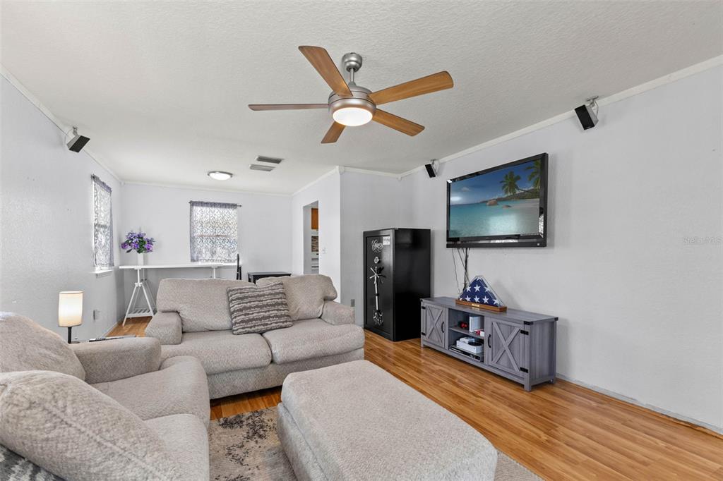 A living room features light-colored sofas, a ceiling fan, a television, and a large safe — 11119 MAHIN LANE, RIVERVIEW, FL