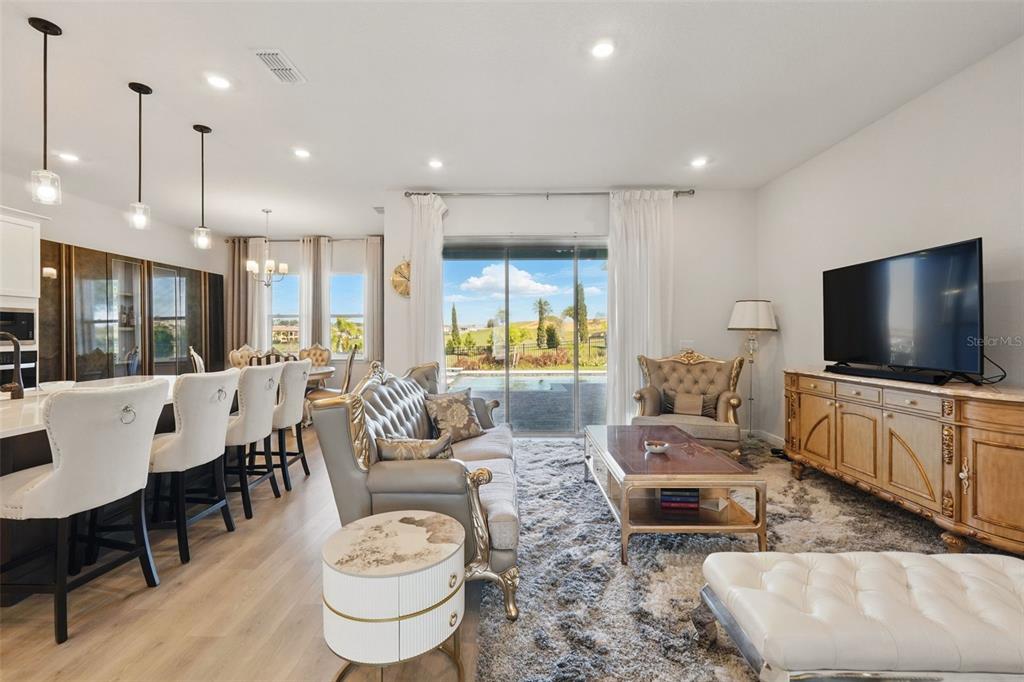 A living room and kitchen area feature a sofa, coffee table, television, and pool view — 16008 VOLTERRA POINT, BELLA COLLINA, FL
