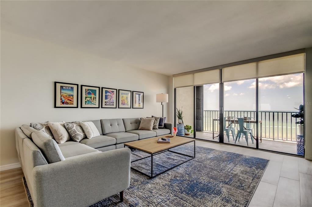 A living room features a large grey sectional sofa, a coffee table, and a balcony view — 1290 GULF BOULEVARD UNIT 1102, CLEARWATER BEACH, FL