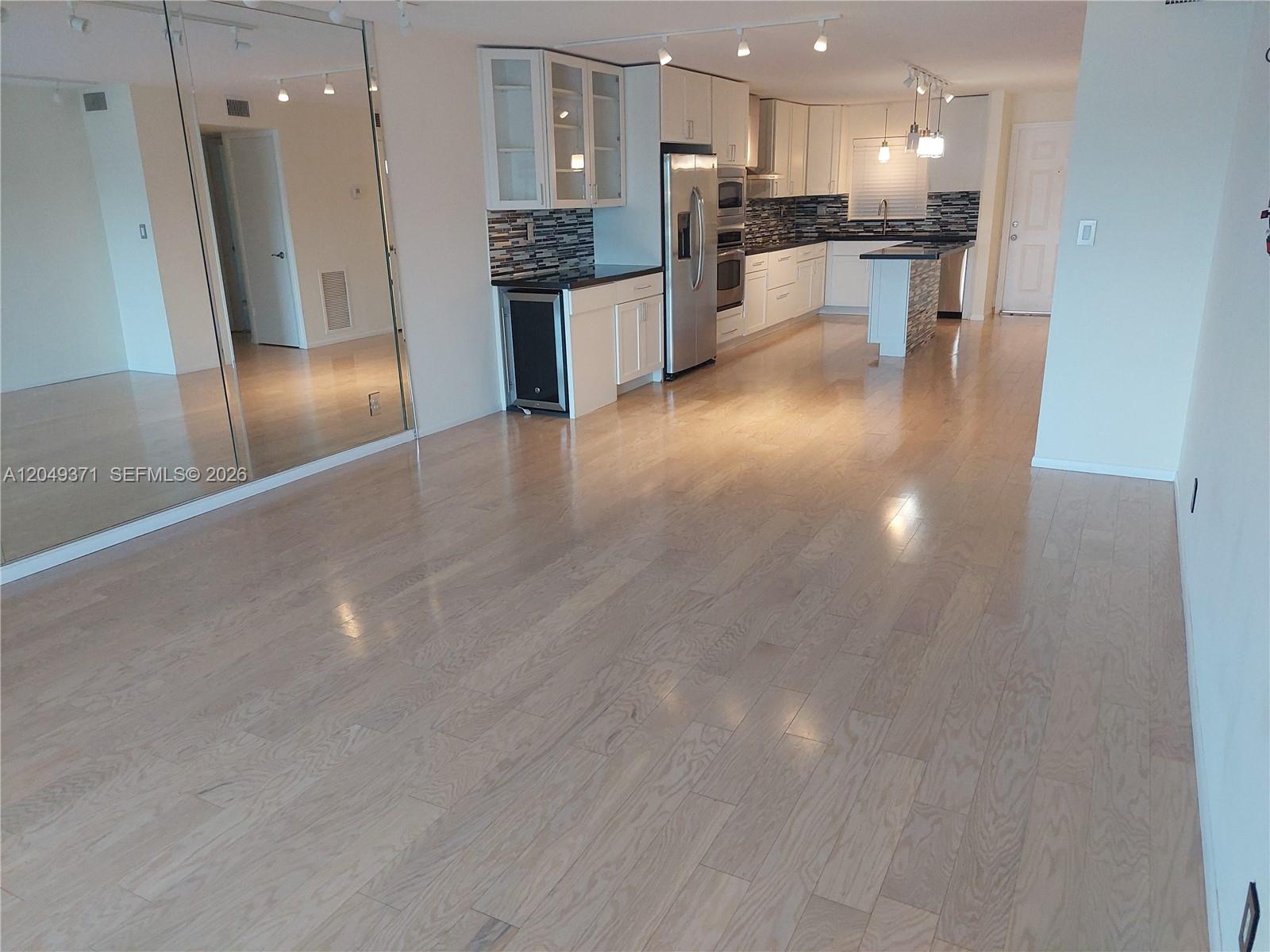 A kitchen with white cabinets, stainless steel appliances, and light wood flooring — FORT LAUDERDALE, FL