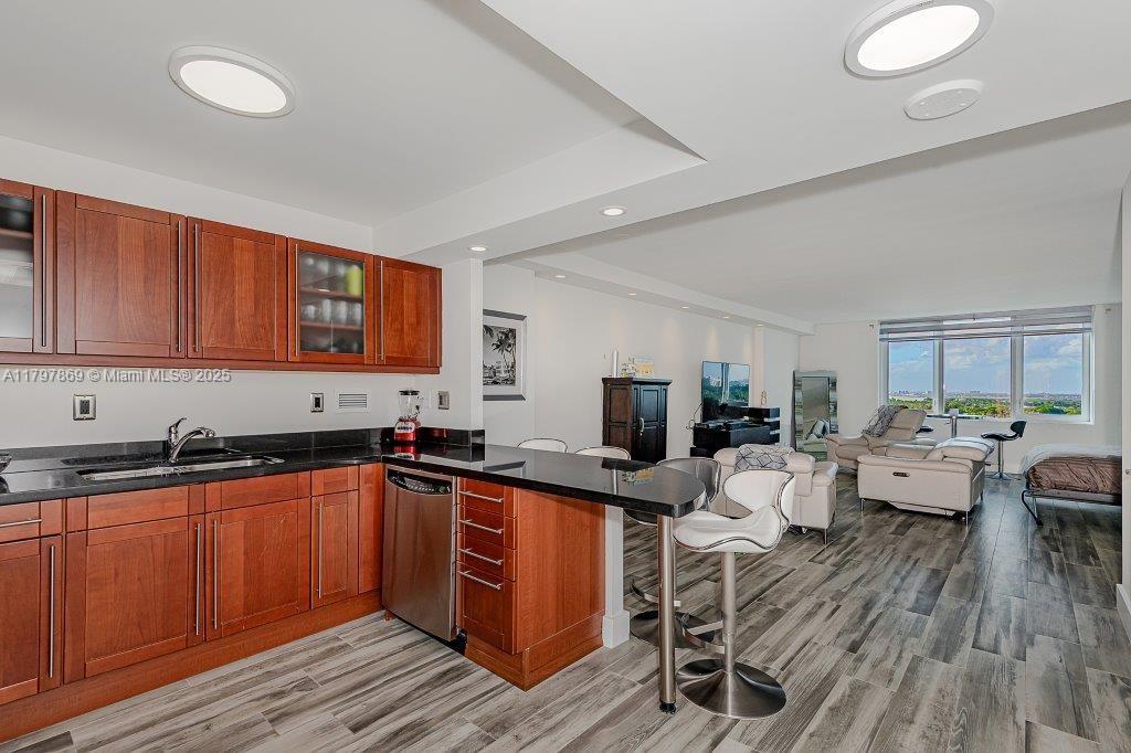 A kitchen with wood cabinets and black countertops opens into a living area with views — 2301 Collins Ave # 1532, Miami Beach FL 33139, MIAMI BEACH, FL