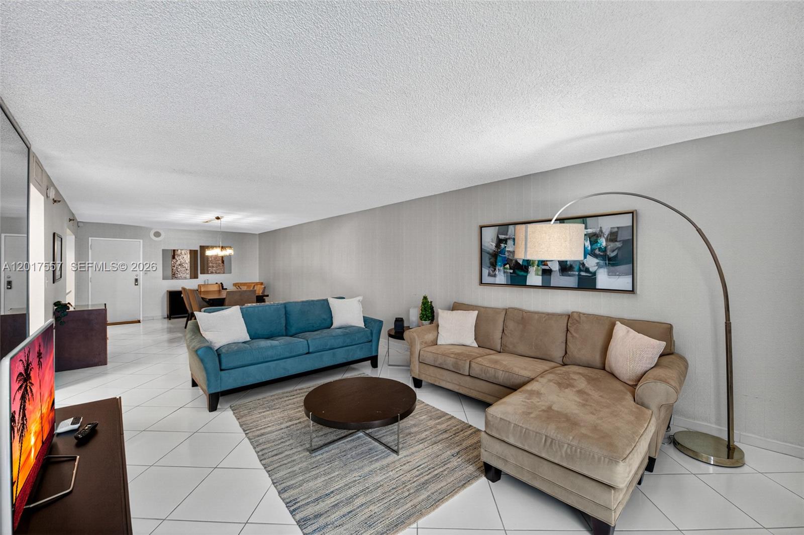 A living room features a blue sofa, a tan sectional, and a large floor lamp — 2401 Collins Ave # 1107, Miami Beach FL 33140, MIAMI BEACH, FL