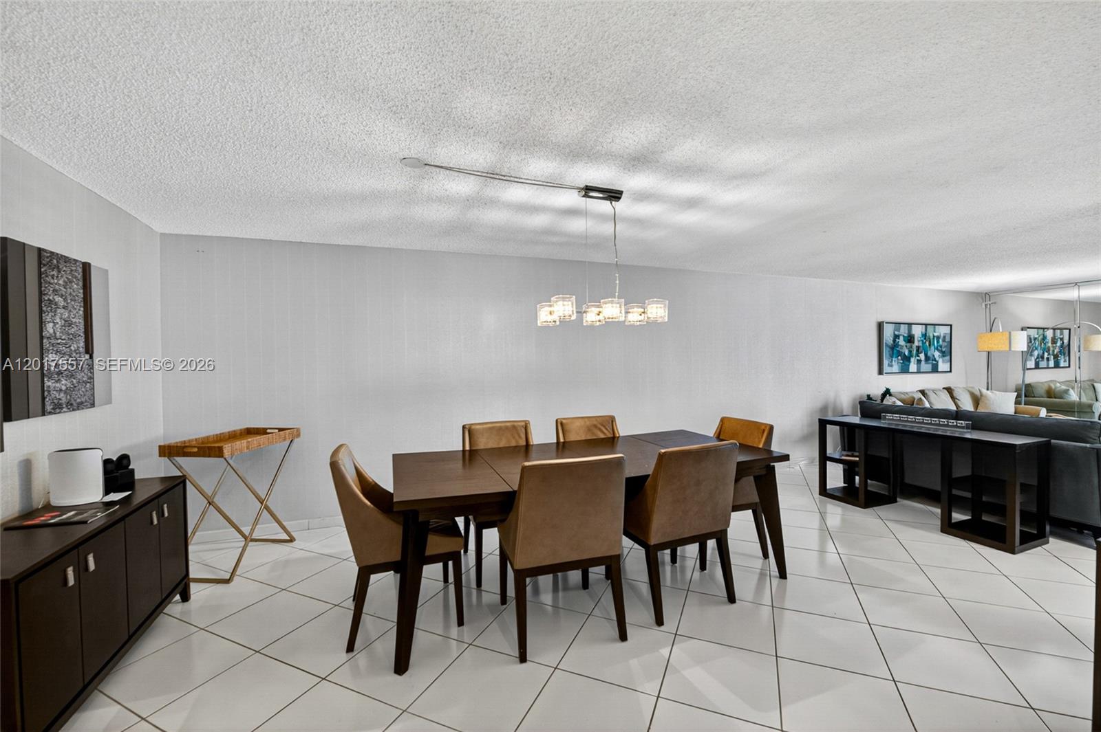 A dining room features a dark wood table, tan chairs, and white tile flooring — 2401 Collins Ave # 1107, Miami Beach FL 33140, MIAMI BEACH, FL