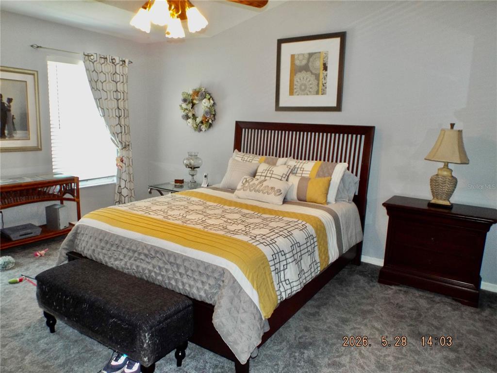 A bedroom features a dark wood bed frame, yellow and gray bedding, and gray carpeting — 13601 FOREST LAKE DRIVE, LARGO, FL