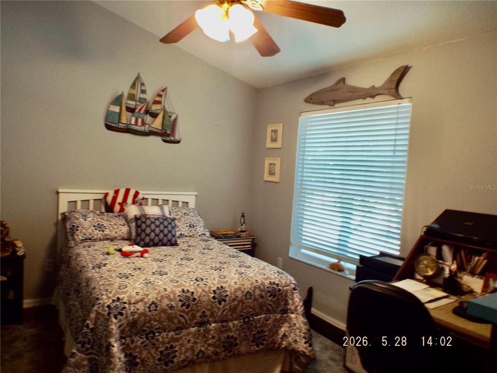 A bedroom features a bed with patterned bedding, a ceiling fan, and nautical wall decor — 13601 FOREST LAKE DRIVE, LARGO, FL