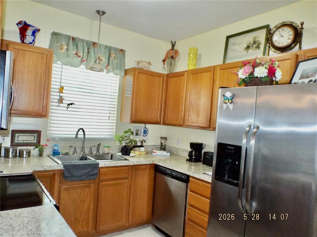 A kitchen features wood cabinets, stainless steel appliances, and light-colored countertops — 13601 FOREST LAKE DRIVE, LARGO, FL