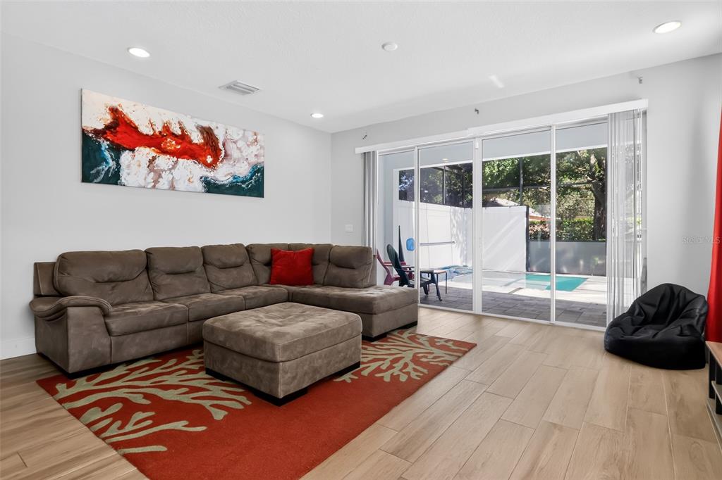 A living room with a sectional sofa, red area rug, and sliding doors to a pool — 17507 HIDDEN FOREST DRIVE, CLERMONT, FL
