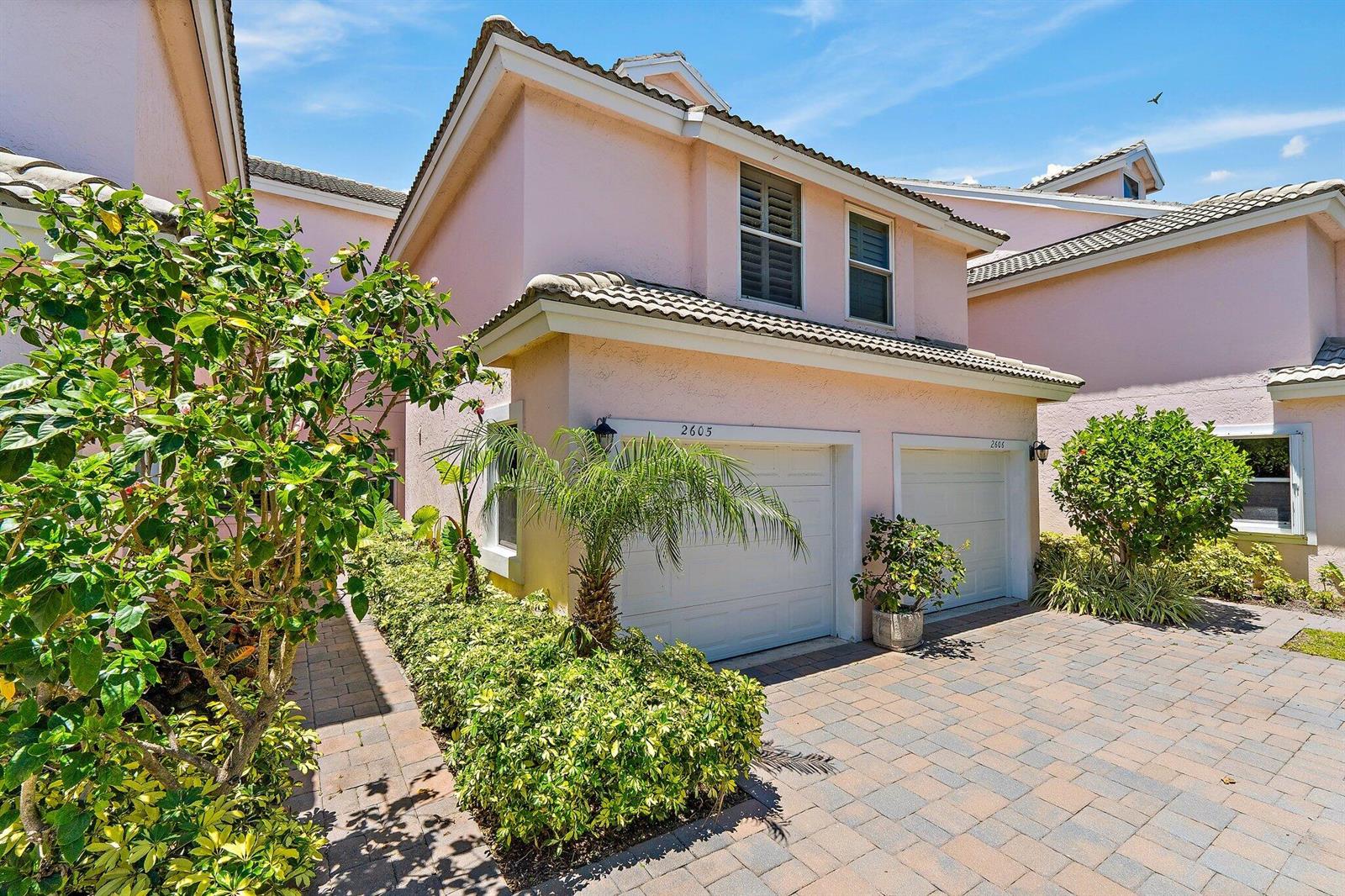 A two-story pink stucco townhouse features two garage doors and a paved driveway — 2605 N Fairway Dr Drive N, Jupiter FL 33477, JUPITER, FL