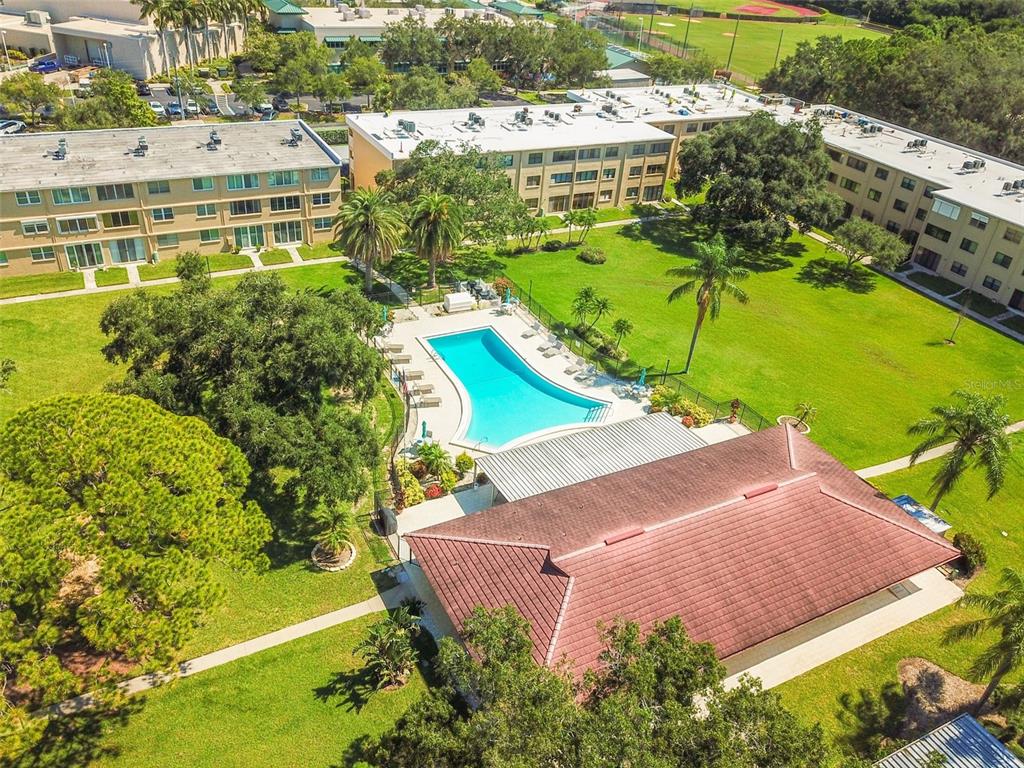 An aerial view of an apartment complex featuring a swimming pool and a clubhouse — 5095 BAY STREET NE UNIT 114, ST PETERSBURG, FL