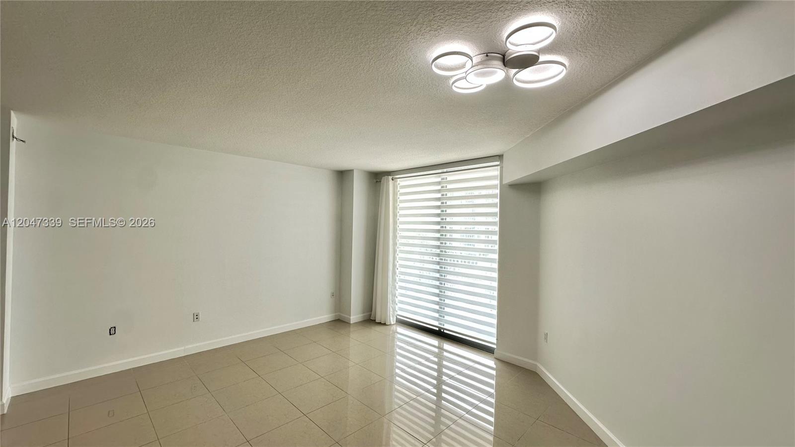 An empty room features light-colored tile flooring, white walls, and a modern ceiling light fixture — 140 S Dixie Hwy # 808, Hollywood FL 33020, HOLLYWOOD, FL