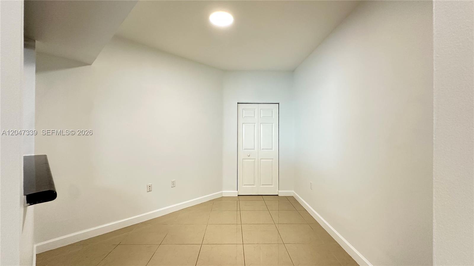 An empty room features light-colored walls, tiled flooring, and a closed white closet door — 140 S Dixie Hwy # 808, Hollywood FL 33020, HOLLYWOOD, FL