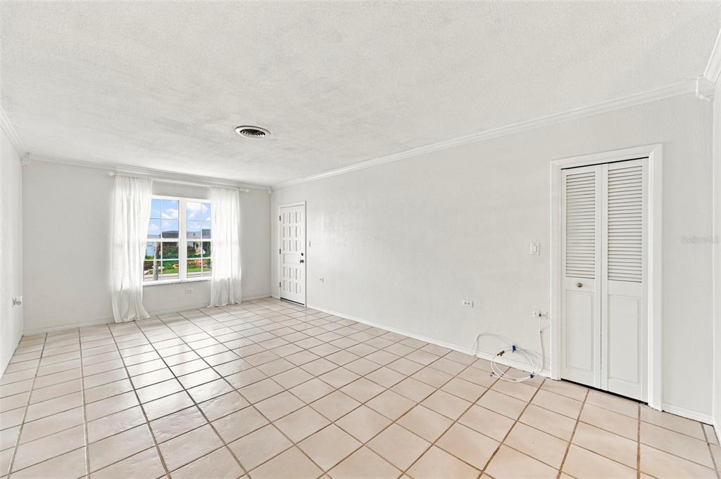A bright, empty living room features white walls, tiled floors, and a white louvered closet — 1342 SNELL ISLE BOULEVARD NE UNIT 4, ST PETERSBURG, FL