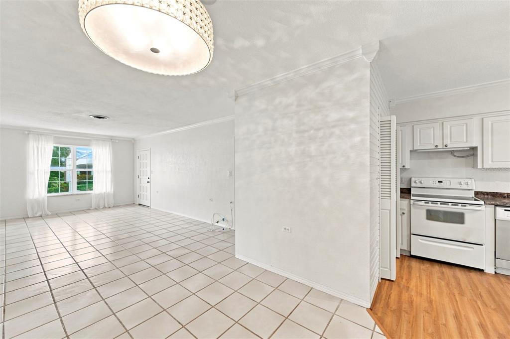An open-concept room features white tile flooring, a large pendant light, and an adjacent kitchen — 1342 SNELL ISLE BOULEVARD NE UNIT 4, ST PETERSBURG, FL