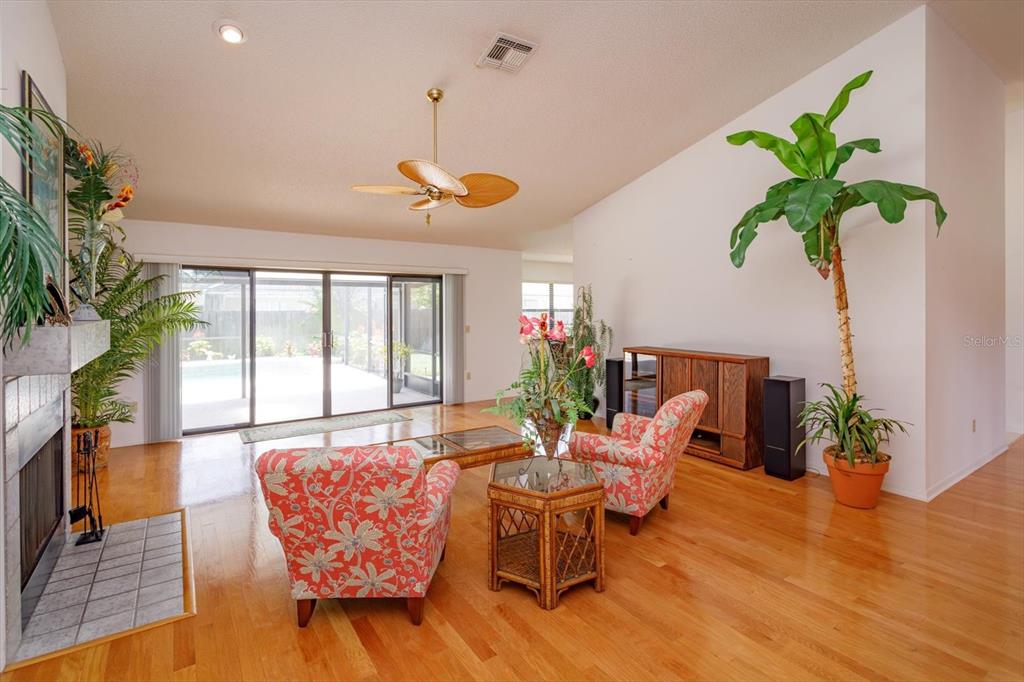 A living room with hardwood floors, a fireplace, two patterned chairs, and a sliding glass door — 1134 SEAFARER LANE, WINTER SPRINGS, FL