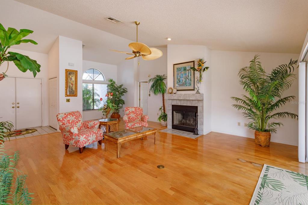 A living room features hardwood floors, a fireplace, two patterned armchairs, and several potted plants — 1134 SEAFARER LANE, WINTER SPRINGS, FL