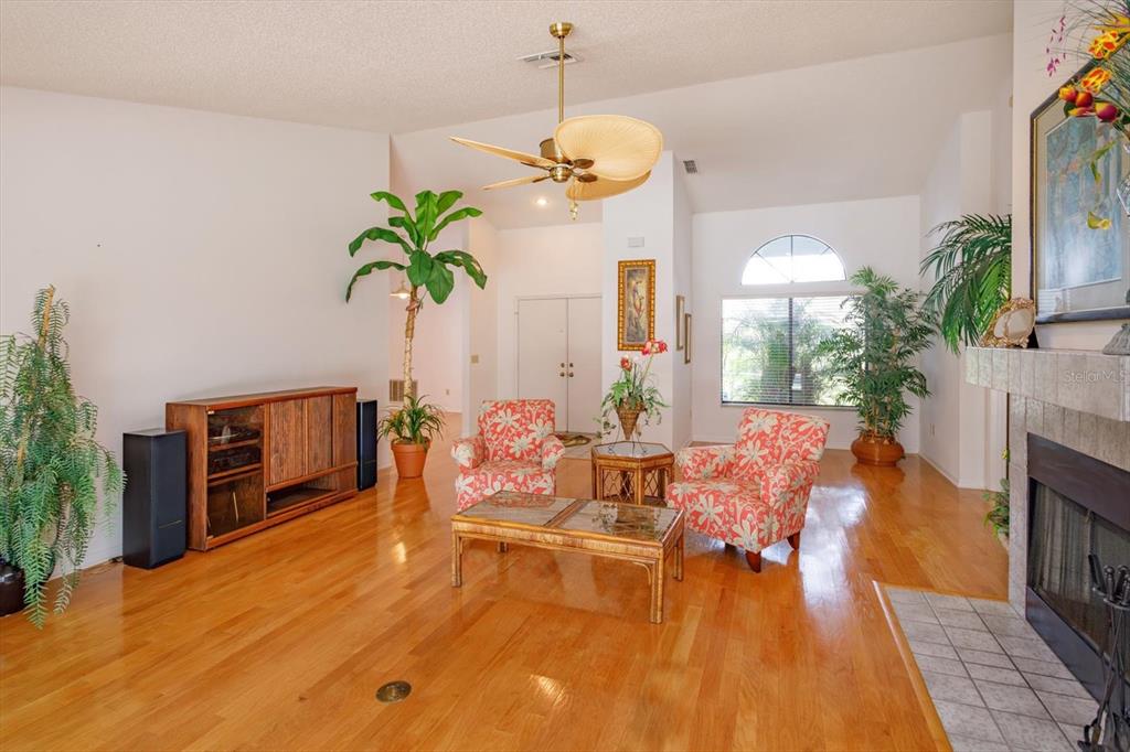 A living room with hardwood floors, a fireplace, two patterned chairs, and a ceiling fan — 1134 SEAFARER LANE, WINTER SPRINGS, FL