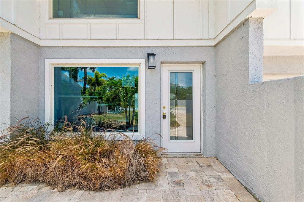 A gray stucco exterior features a white front door and a large window with landscaping — 970 BOCA CIEGA ISLE DRIVE, ST PETE BEACH, FL