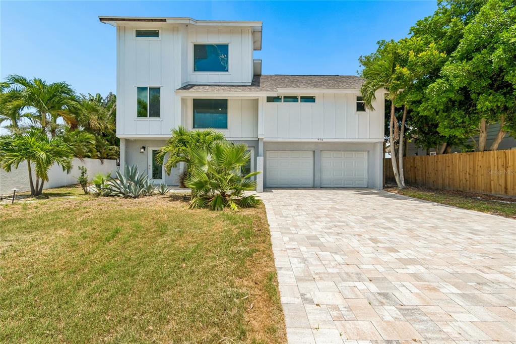 A two-story white house with a paved driveway, a two-car garage, and tropical landscaping — 970 BOCA CIEGA ISLE DRIVE, ST PETE BEACH, FL