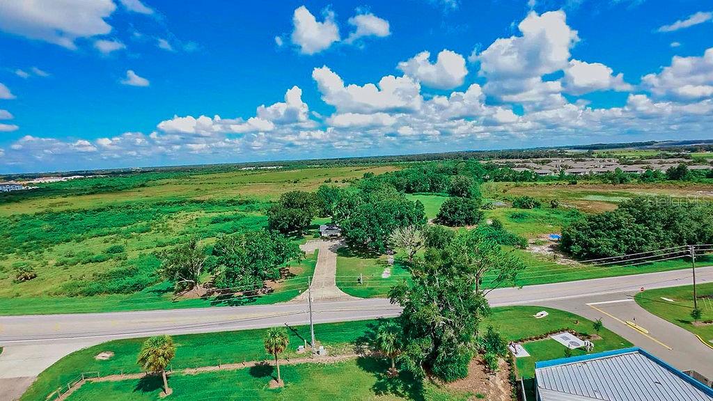An aerial view shows a house surrounded by trees and fields next to a road — 1030 CHALET SUZANNE ROAD, LAKE WALES, FL