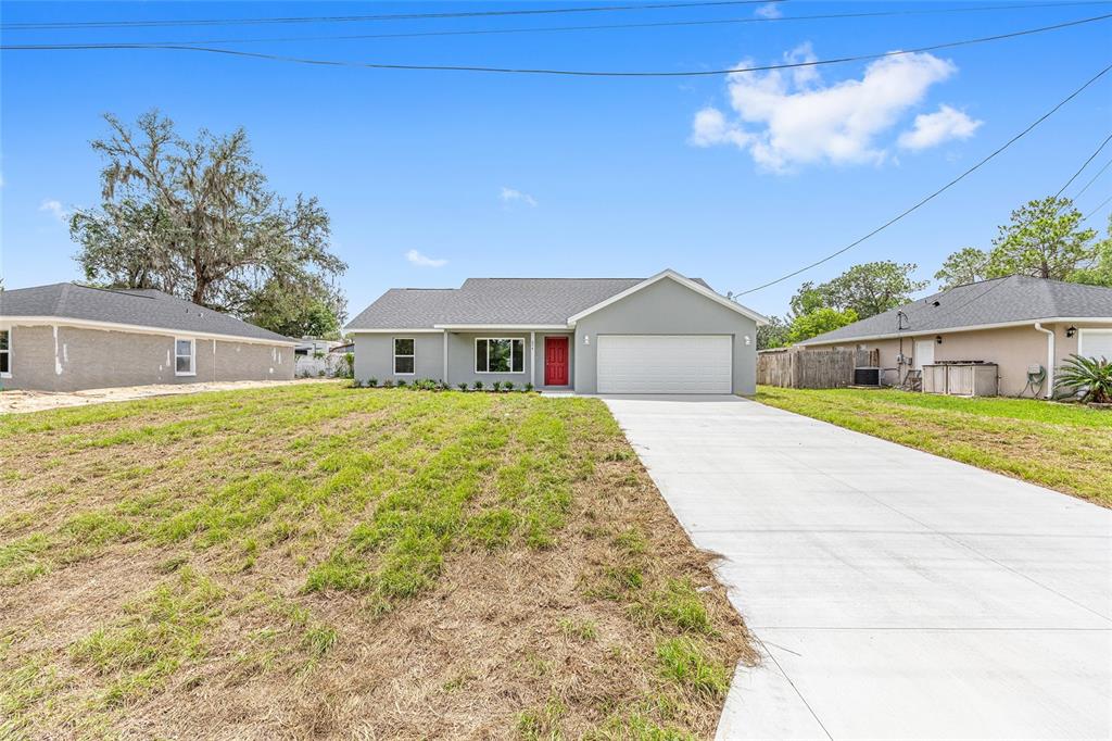 A gray single-story house with a red front door and a concrete driveway — 654 NE 130TH COURT, SILVER SPRINGS, FL