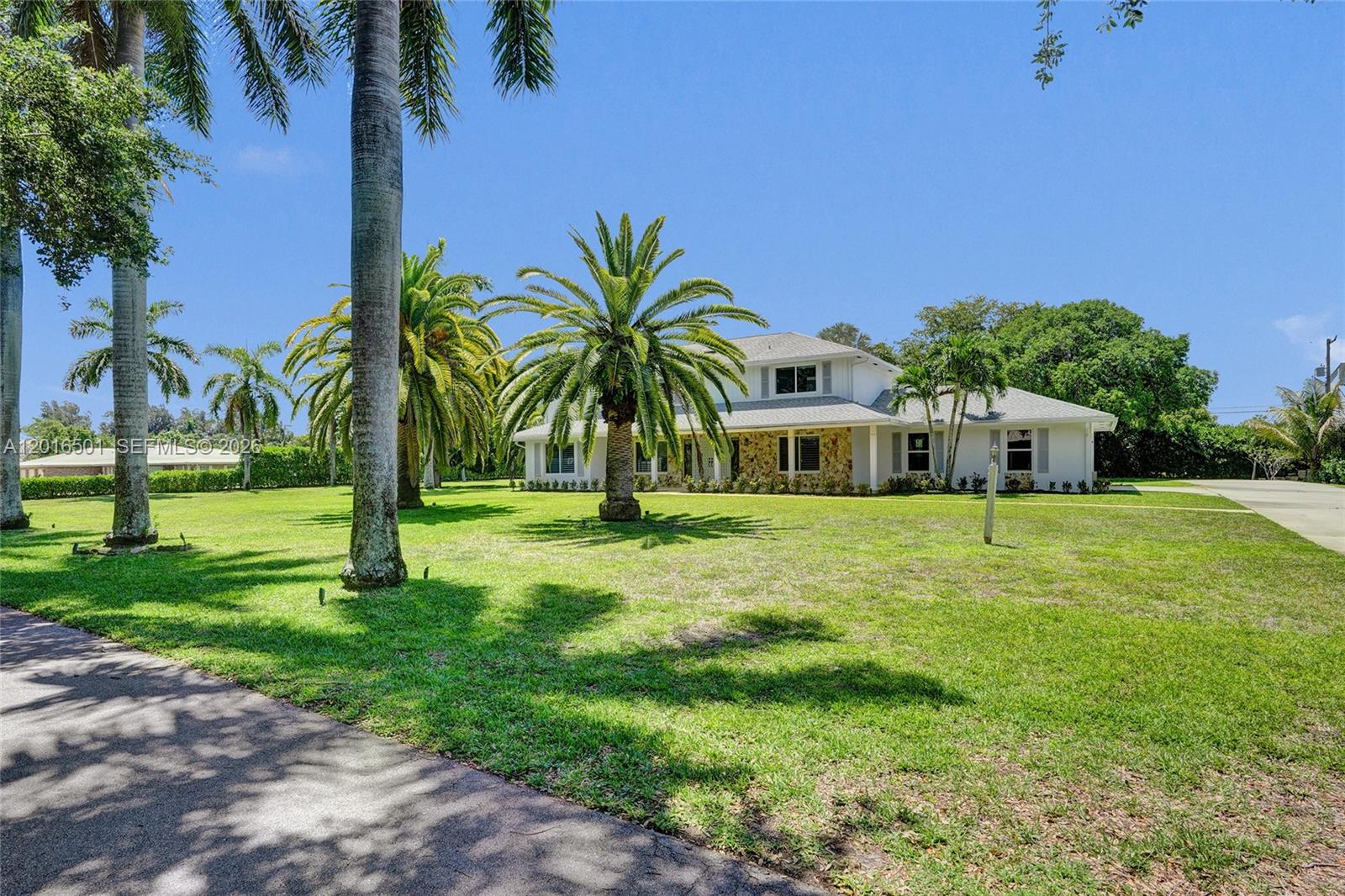 A two-story white house with stone accents sits on a large, palm-filled grassy lawn — 4024 Frances Dr, Delray Beach FL 33445, DELRAY BEACH, FL