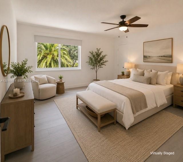 This virtually staged bedroom features light wood floors, a ceiling fan, and a large window — 4024 Frances Dr, Delray Beach FL 33445, DELRAY BEACH, FL
