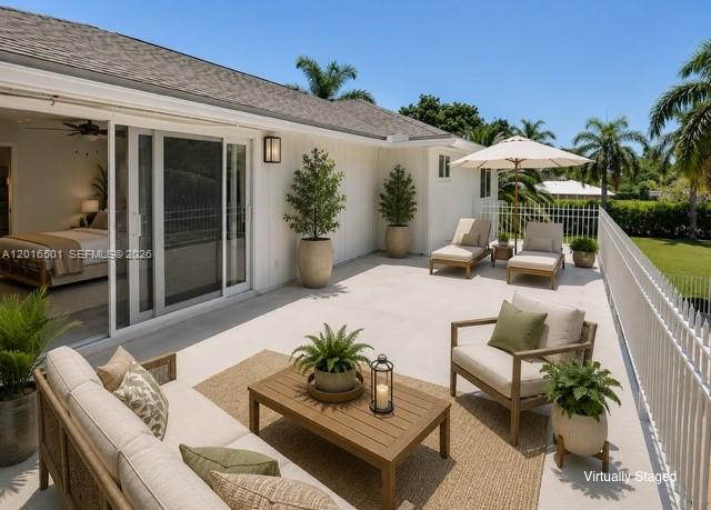 A patio with outdoor furniture, a white fence, and a view of palm trees — 4024 Frances Dr, Delray Beach FL 33445, DELRAY BEACH, FL
