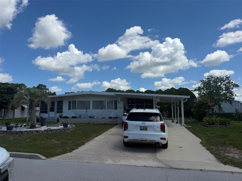 A white single-story manufactured home with a carport and a driveway in front — 14327 EVERMORE STREET, BROOKSVILLE, FL