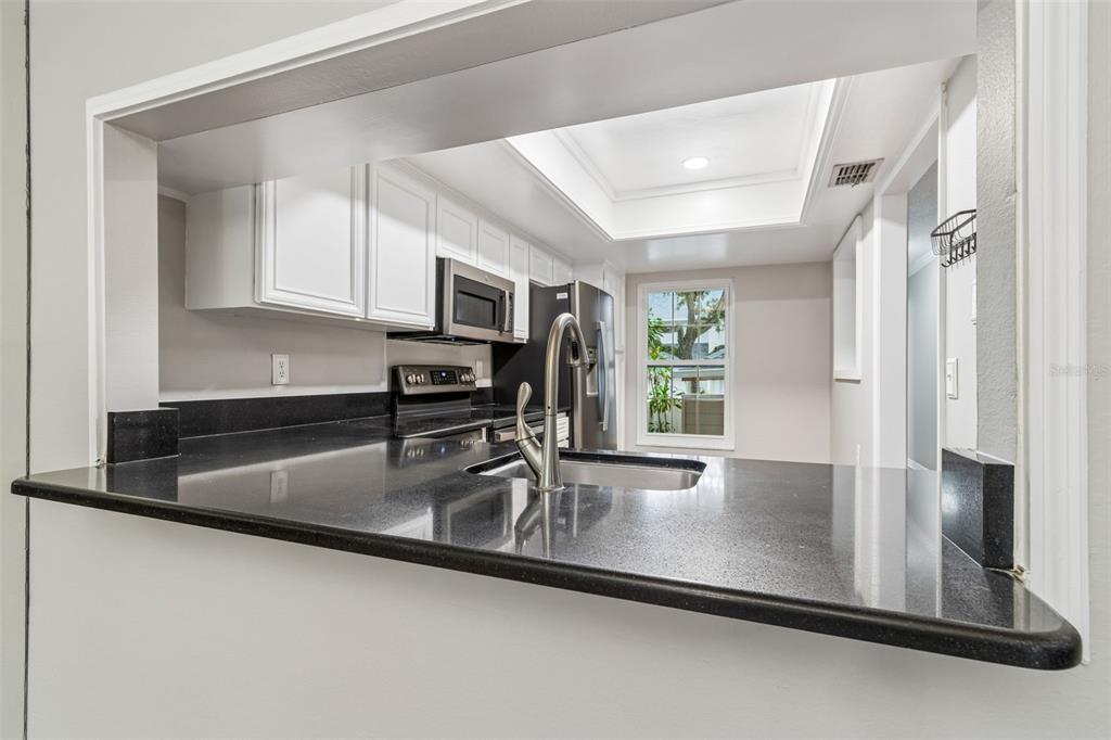 A hallway with hardwood floors leads to a carpeted staircase with a metal railing — 5203 BAYSHORE BOULEVARD UNIT 5, TAMPA, FL