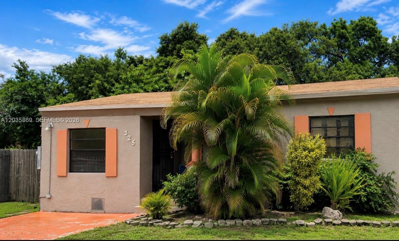 A single-story house with a tan exterior, orange shutters, and a large palm tree — 325 NW 56th St, Miami FL 33127, MIAMI, FL