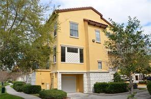 A three-story yellow stucco townhouse with a ground-level garage and stone veneer base — 6121 METROWEST BOULEVARD UNIT 101, ORLANDO, FL