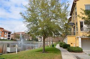 A view of a pond with a fountain next to a multi-story yellow apartment building — 6121 METROWEST BOULEVARD UNIT 101, ORLANDO, FL