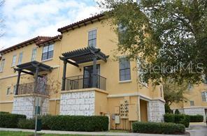 A three-story yellow stucco building features stone accents, dark wood pergolas, and balconies — 6121 METROWEST BOULEVARD UNIT 101, ORLANDO, FL