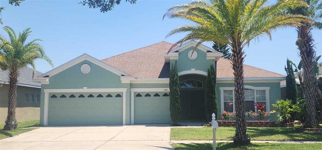 A single-story house with a light green exterior, a two-car garage, and two palm trees — 1829 MIRA LAGO CIRCLE, RUSKIN, FL