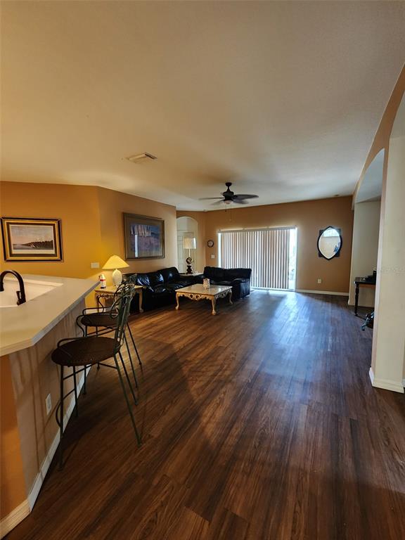 A living room with dark wood flooring, a kitchen counter, and black leather furniture — 1829 MIRA LAGO CIRCLE, RUSKIN, FL