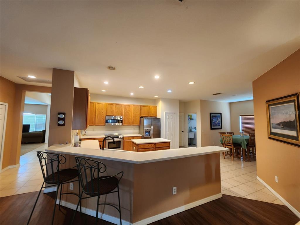 A kitchen with wood cabinets, stainless steel appliances, and a breakfast bar overlooks a dining area — 1829 MIRA LAGO CIRCLE, RUSKIN, FL
