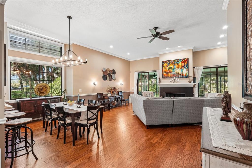 An open-concept living and dining area features hardwood floors, a fireplace, and large windows — 5676 PIPERS WAITE UNIT 56, SARASOTA, FL