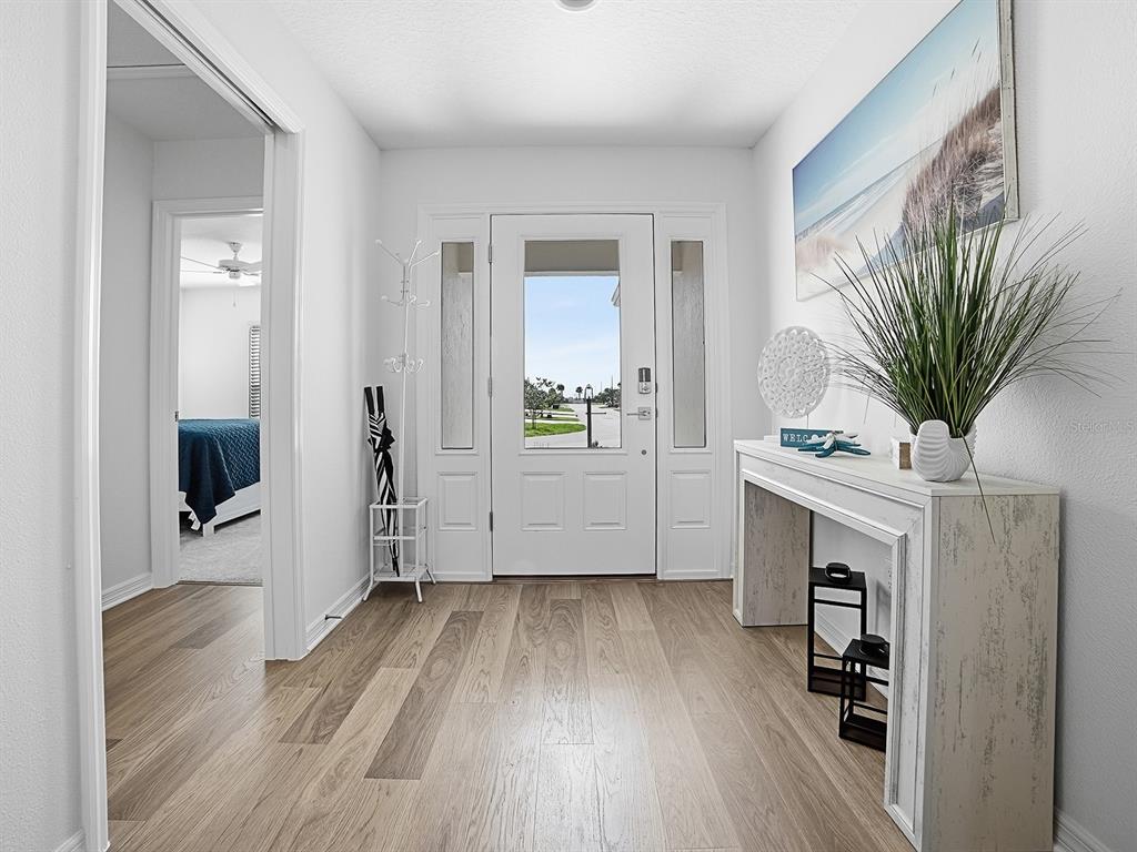 A bright entryway features light wood flooring, a white front door, and a console table — 7274 CARLOS COURT, THE VILLAGES, FL