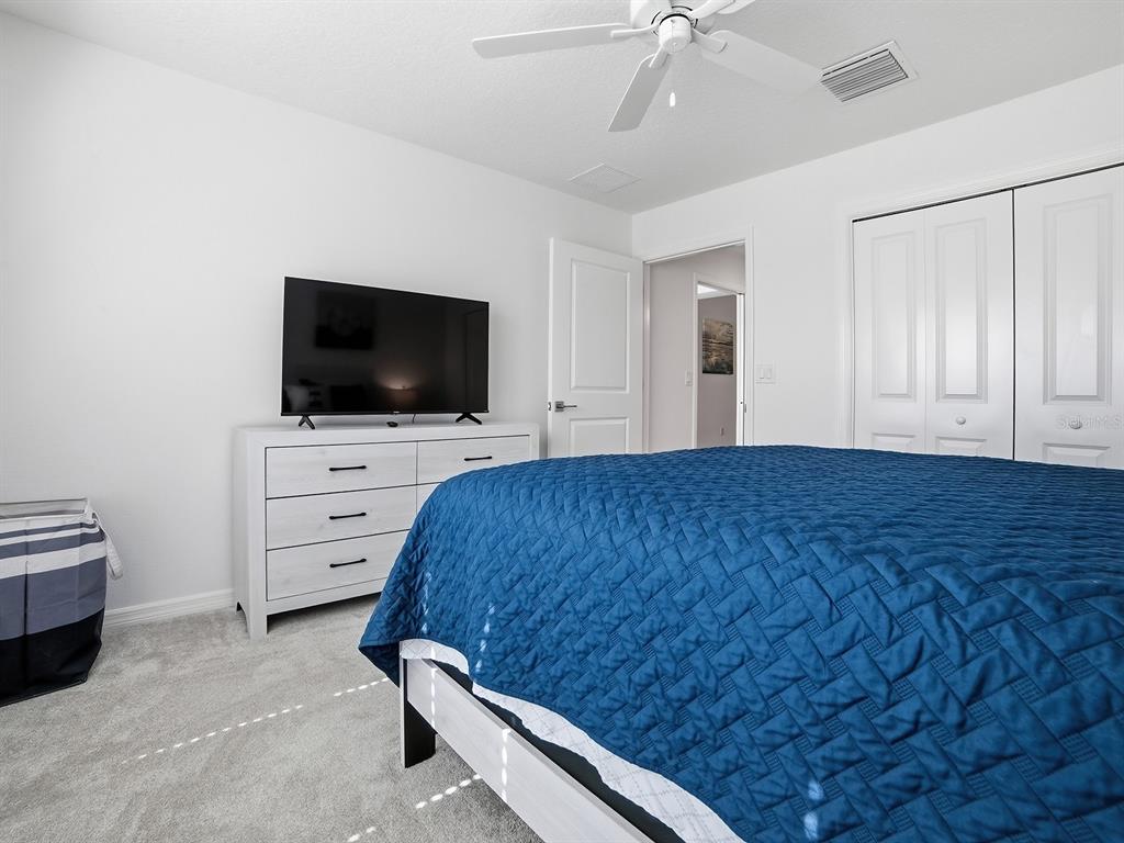 A bedroom features a blue quilt on a bed, a white dresser, and a television — 7274 CARLOS COURT, THE VILLAGES, FL