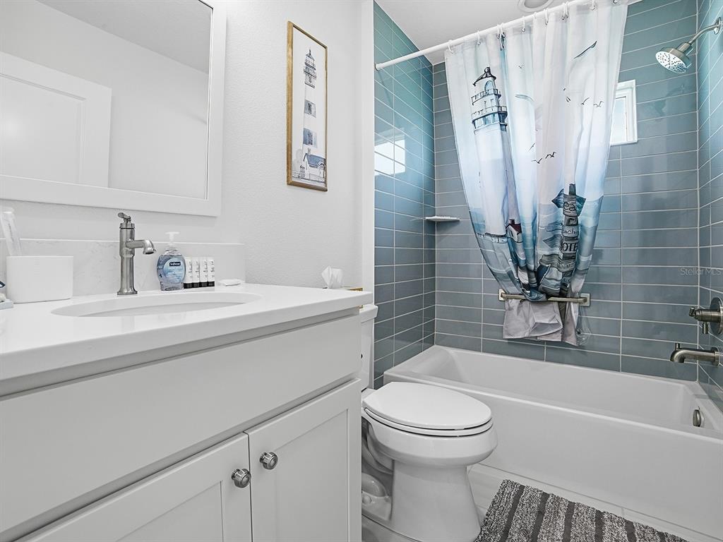 A bathroom features a white vanity, a toilet, and a bathtub with blue subway tiles — 7274 CARLOS COURT, THE VILLAGES, FL