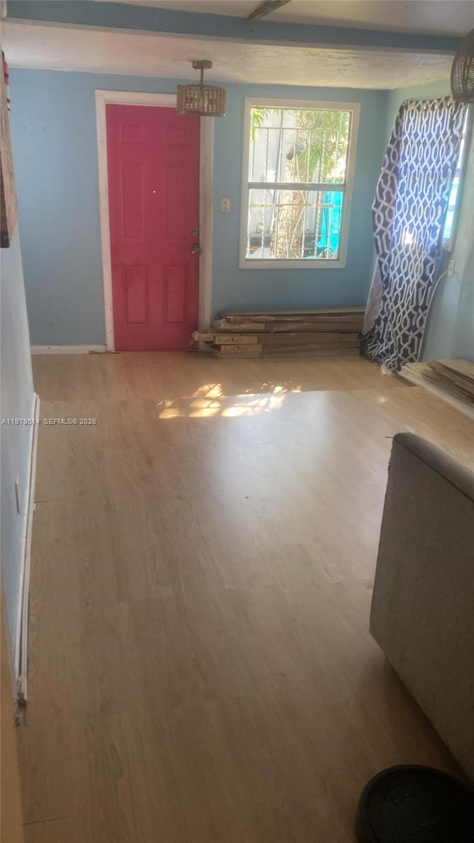 A room with light wood-look flooring, light blue walls, and a bright pink door — 2239 Sheridan St, Hollywood FL 33020, HOLLYWOOD, FL
