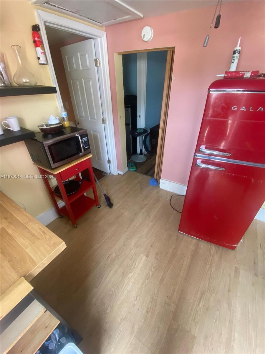 A kitchen features a red retro-style refrigerator, a microwave on a red cart, and light-colored flooring — 2239 Sheridan St, Hollywood FL 33020, HOLLYWOOD, FL
