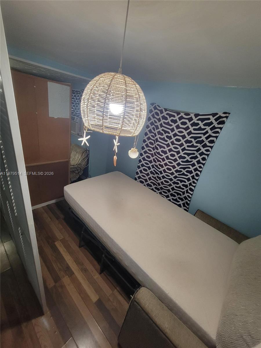 A small bedroom features a single bed, a woven pendant light, and wood-look flooring — 2239 Sheridan St, Hollywood FL 33020, HOLLYWOOD, FL