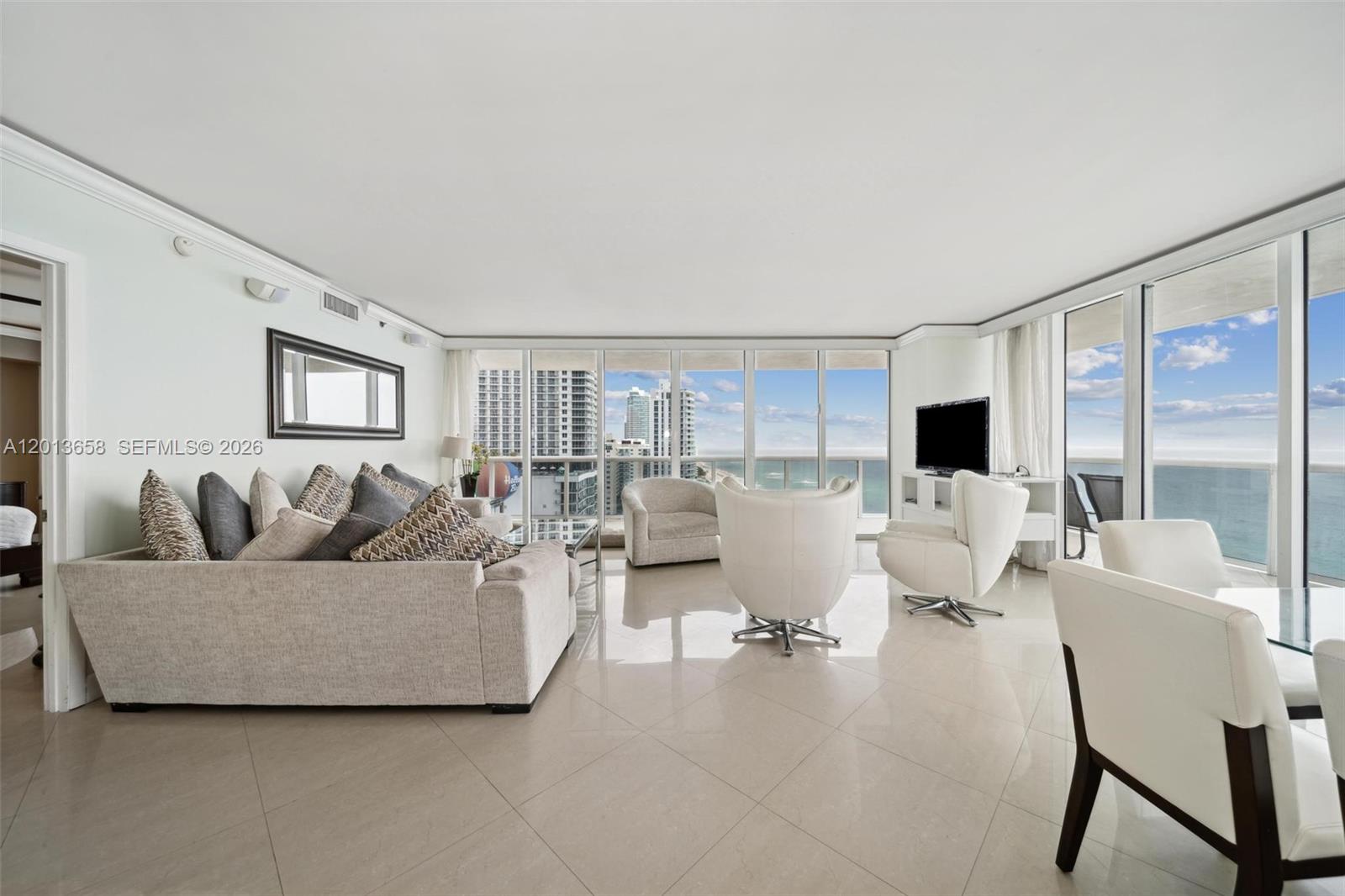 A bright living room features light tile floors, modern furniture, and floor-to-ceiling windows with ocean views — 1830 S Ocean Dr # 1701, Hallandale Beach FL 33009, HALLANDALE BEACH, FL
