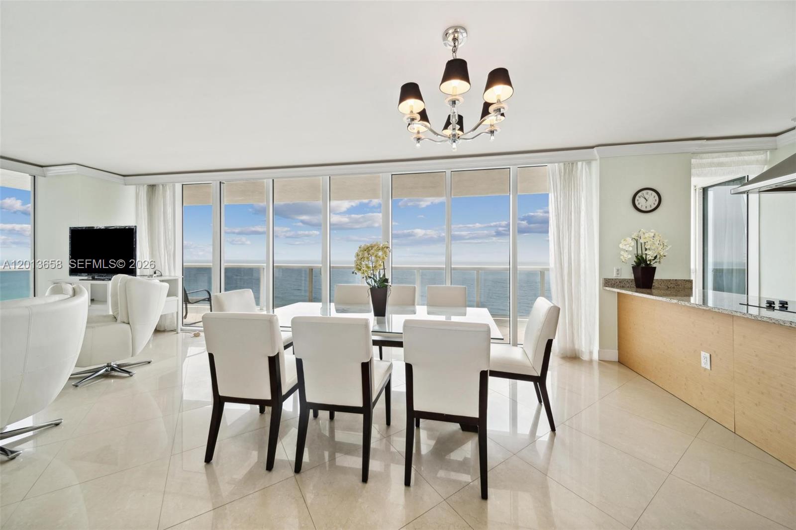 A dining area features a glass table, white chairs, and floor-to-ceiling windows overlooking the ocean — 1830 S Ocean Dr # 1701, Hallandale Beach FL 33009, HALLANDALE BEACH, FL